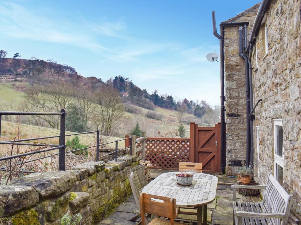een patio met een tafel en stoelen en een stenen gebouw bij Rowan Cottage in Rosedale Abbey