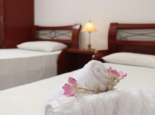 a hotel room with two beds with white sheets and pink flowers at Villa Anna in Hanioti