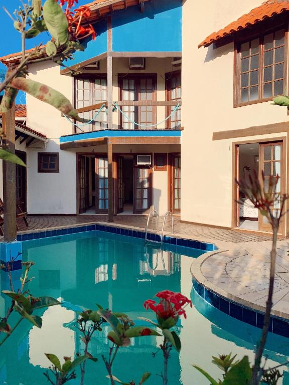 a villa with a swimming pool in front of a house at Pousada Kaianoá in Arraial do Cabo