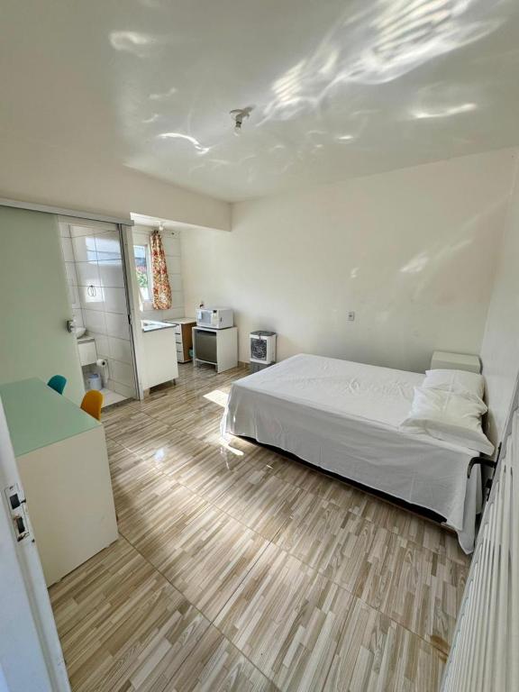 Schlafzimmer mit einem weißen Bett und Holzboden in der Unterkunft Apartamento 01 Vila Telebrasília in Brasilia