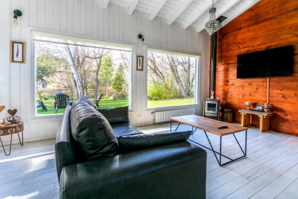 a living room with a leather couch and a table at BOG Nórdica 2 in Villa La Angostura