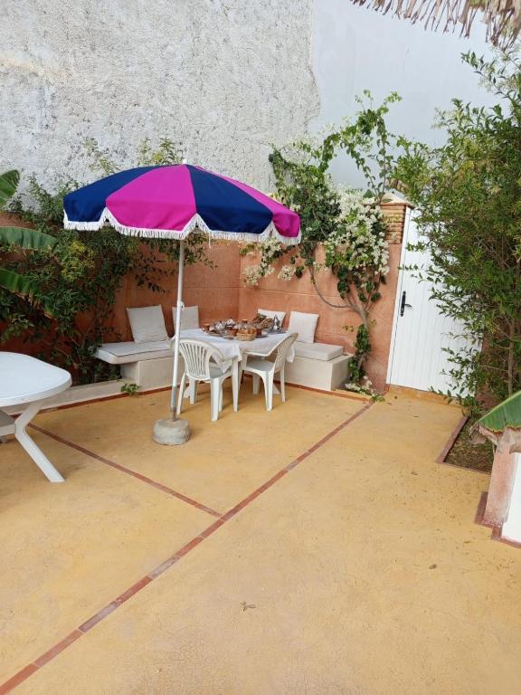 a patio with a table and chairs and an umbrella at APPARTEMENT surf camp pour les familles in Oualidia