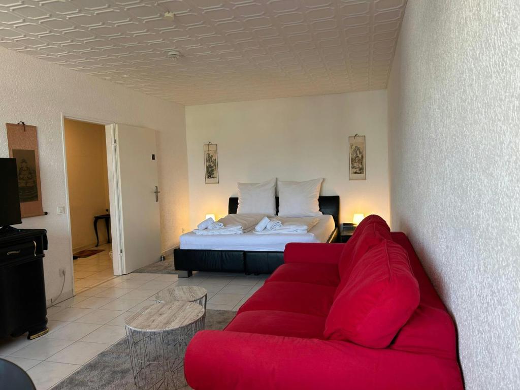 a living room with a red couch and a bed at Central Studio for 2 in Hattersheim