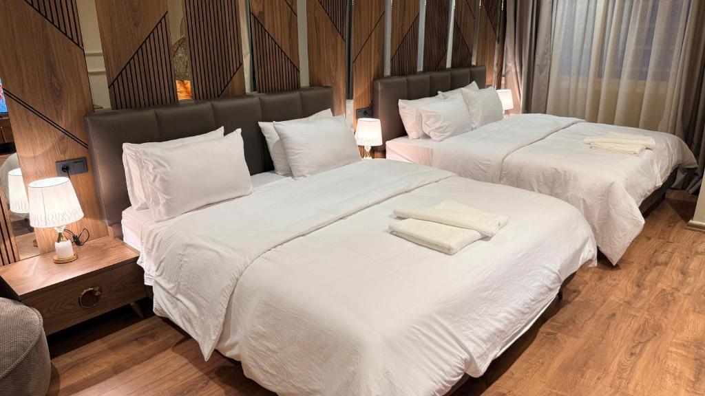 two beds in a hotel room with white sheets and towels at Suite Bahiya 11 in Fès