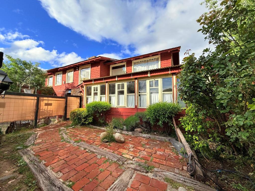 a red house with a brick driveway in front of it at Tres Coronas in San Martín de los Andes