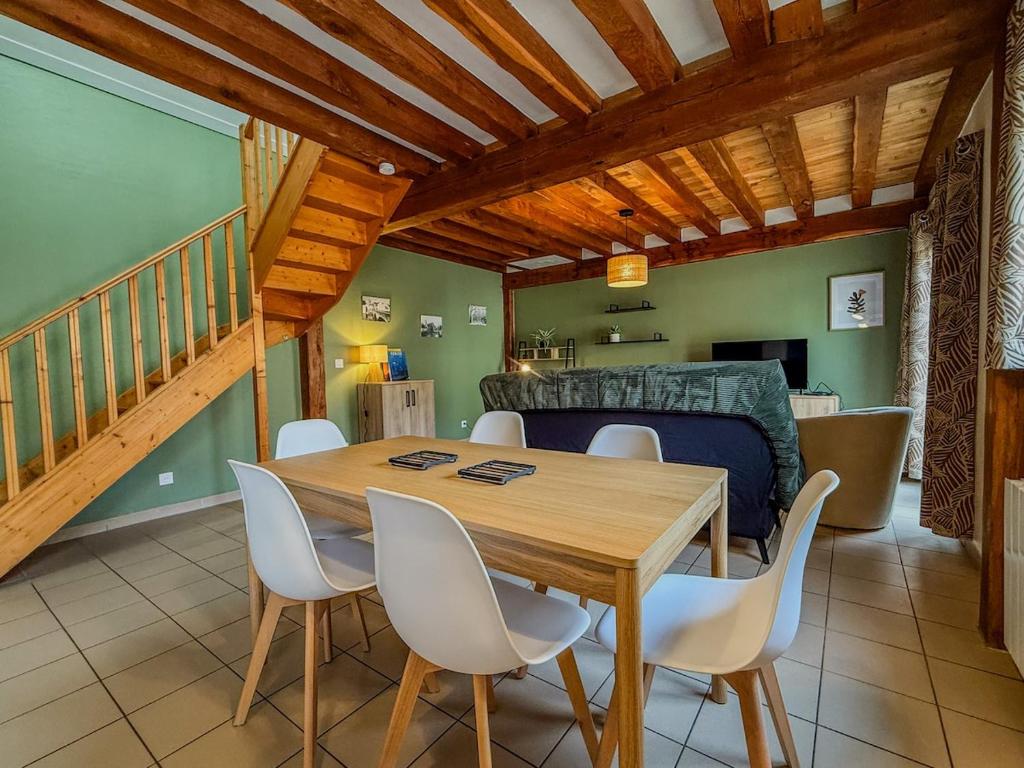 ein Esszimmer mit einem Holztisch und weißen Stühlen in der Unterkunft Maison avec parking à 10min du centre-ville à pied in Chartres