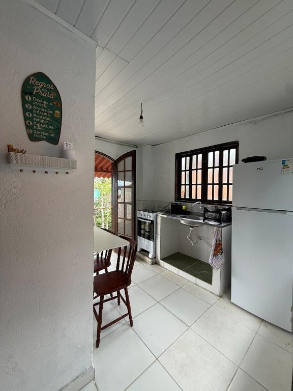 a kitchen with a table and a white refrigerator at Charming Chalet Village Historic Center in Ilhabela