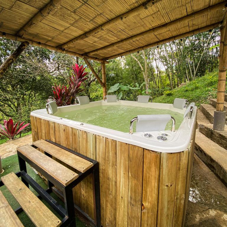 a bath tub sitting under a pergola with a bench at EcoHotel Casa Maria Parda in Cocorná