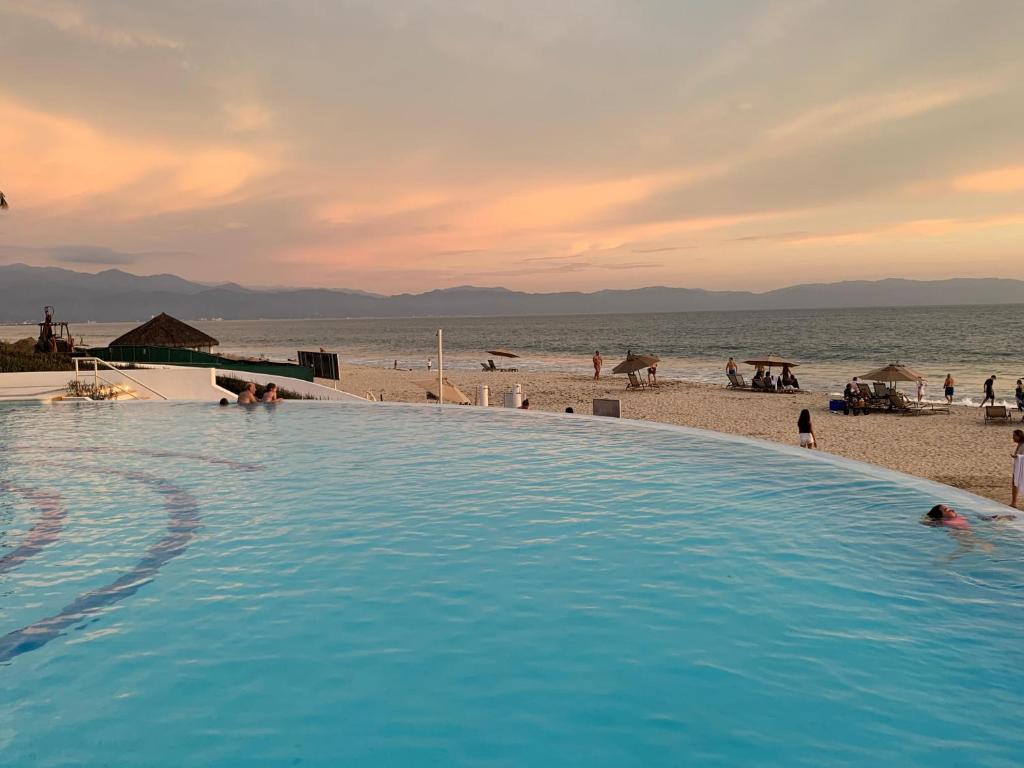 a large swimming pool next to a beach with people at Puerto Vallarta Del Canto Luxury in Bucerías