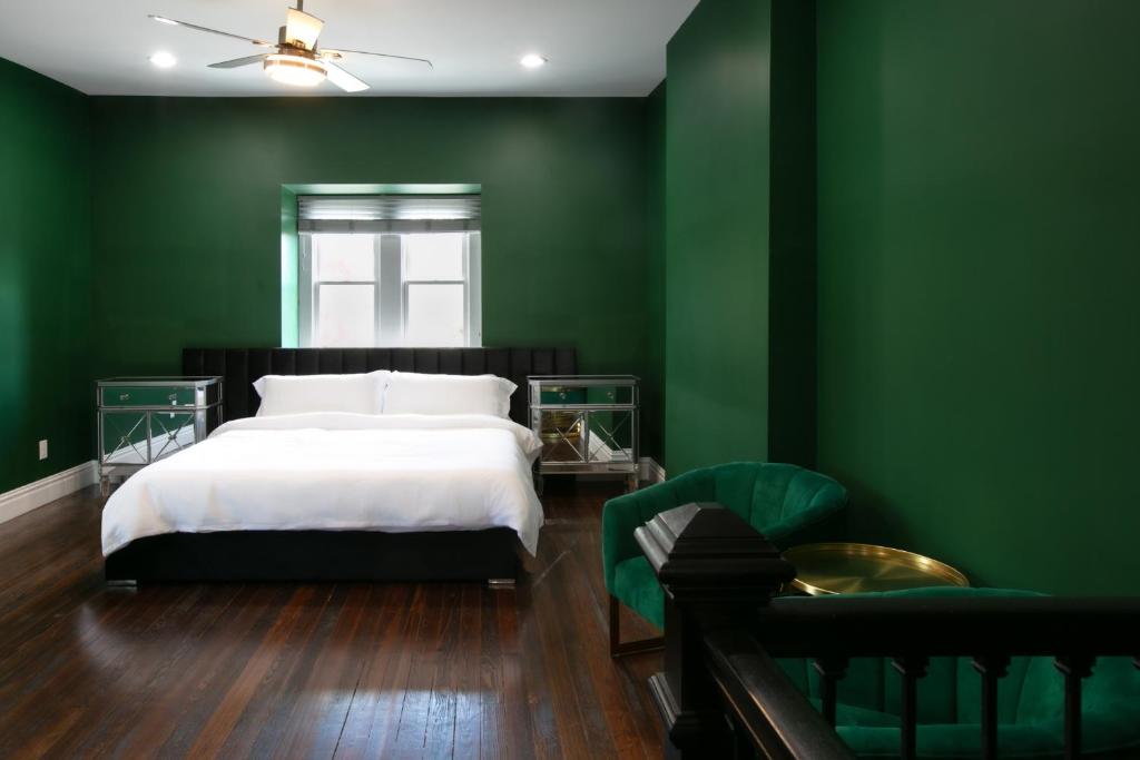 ein grünes Schlafzimmer mit einem Bett und einem Stuhl in der Unterkunft The Celestial House by StayLage in Soulard