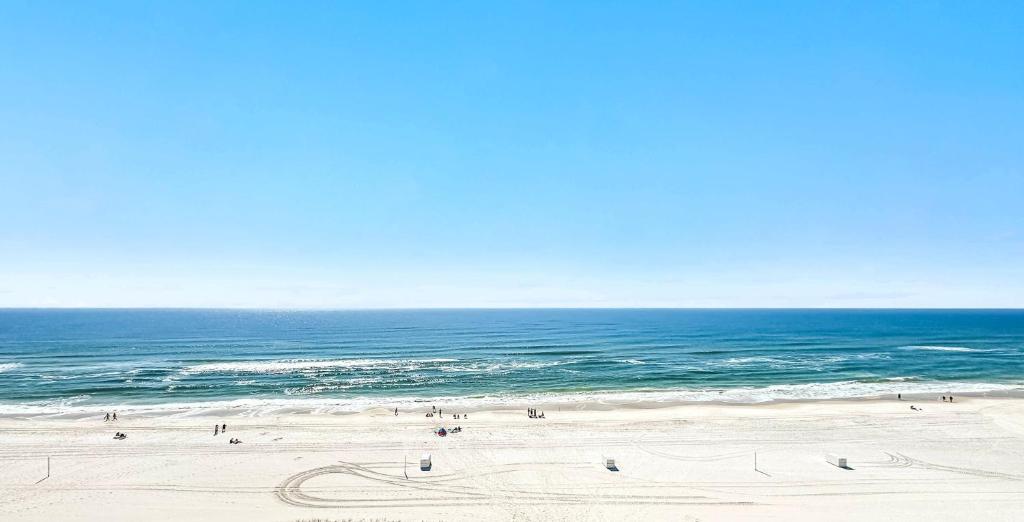 a group of people on a beach near the ocean at Beachfront Bliss! 1800 sq ft Spacious 3BR Sleeps 12 - Oceans 9D in Gulf Shores