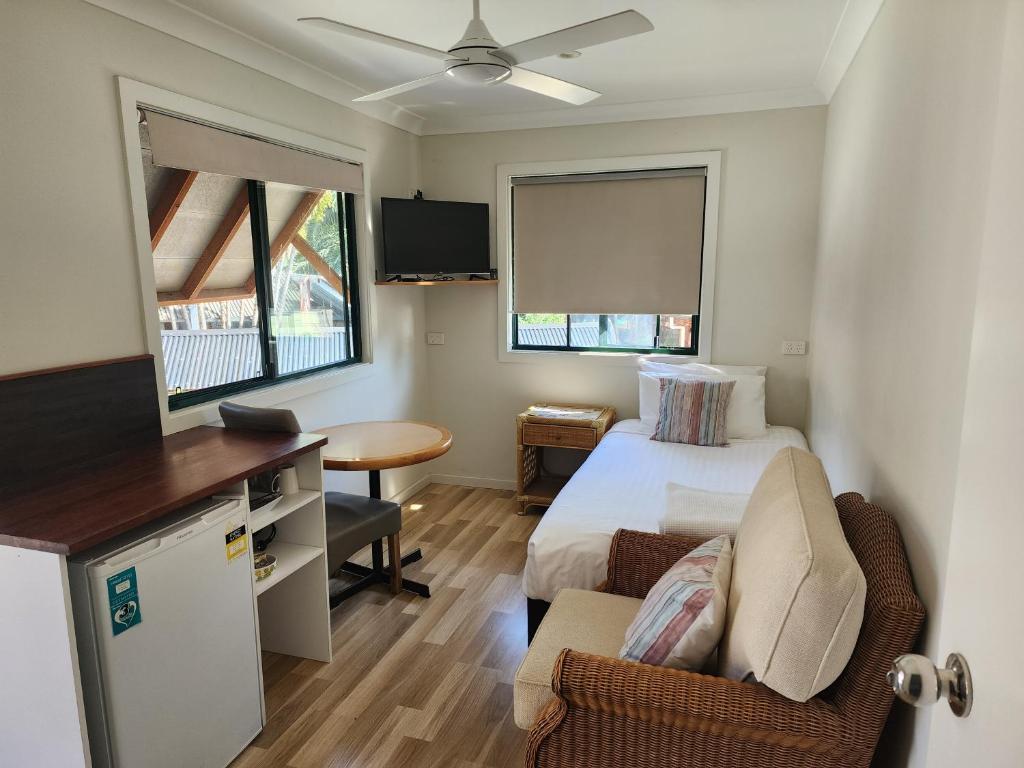 Una habitación de hotel con una cama, un escritorio y un televisor. en T's Resort & Motel, en Port Macquarie