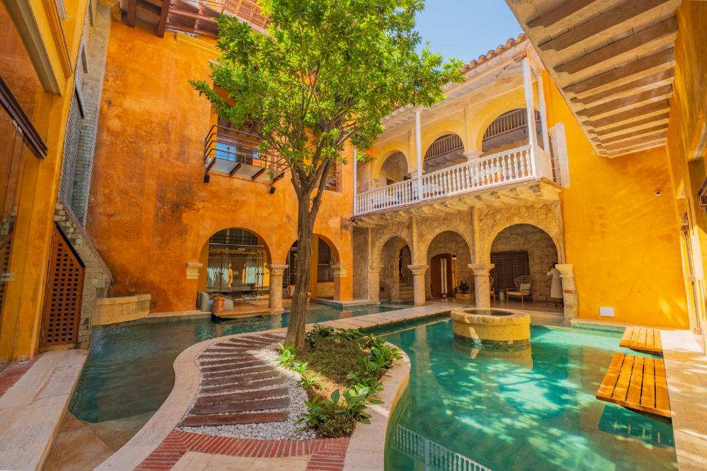 an indoor pool in a building with a tree in it at Casa Carolina Luxury Wellness Hotel in Cartagena de Indias