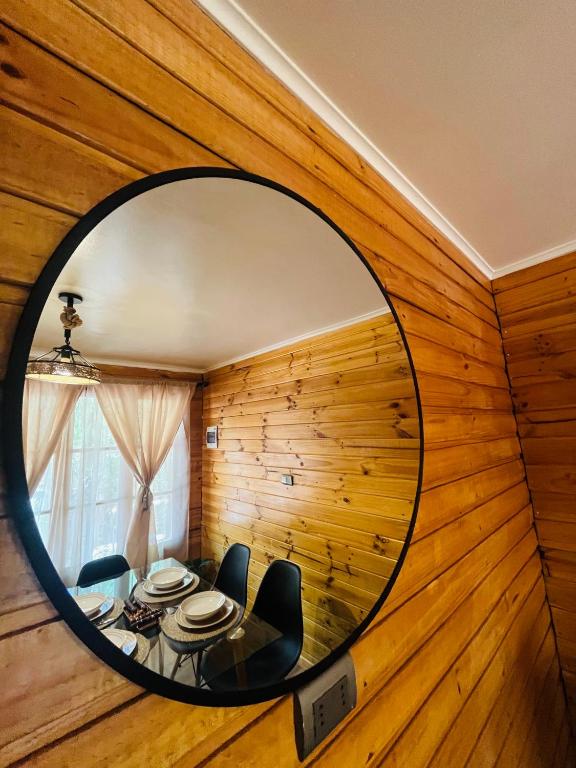 a circular mirror in a room with a table and chairs at Cabañas Piedra Viva 2 in San Pedro de Atacama