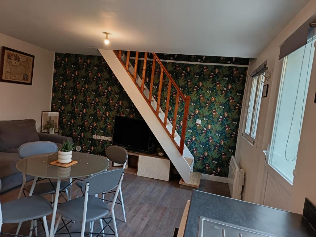 a living room with a table and a staircase at Charmant petit logement in Bayeux