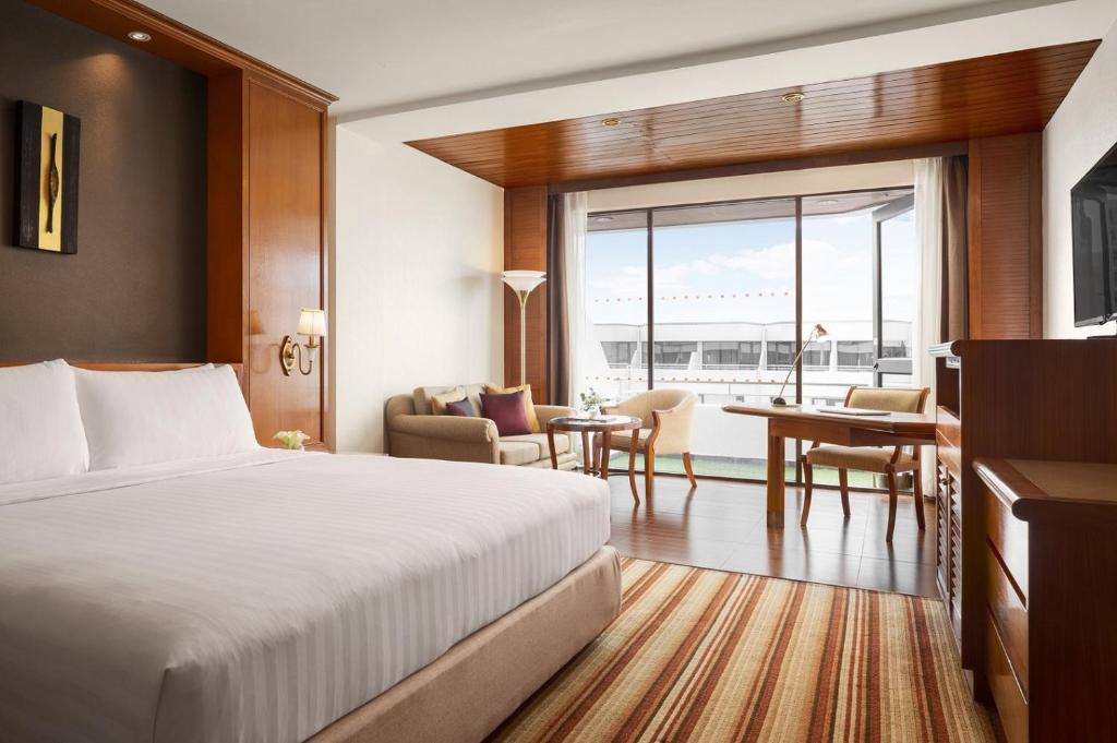 A larger traditional-style bedroom with a sitting area and broad airport-facing window.