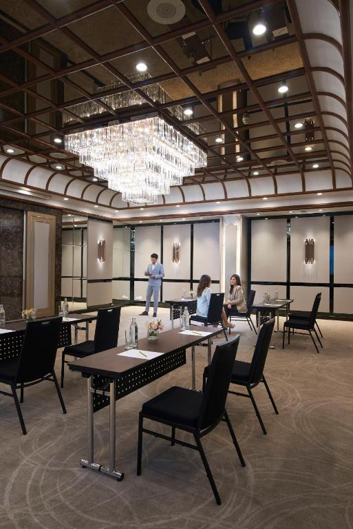 A smaller meeting room with scattered tables beneath a large chandelier.
