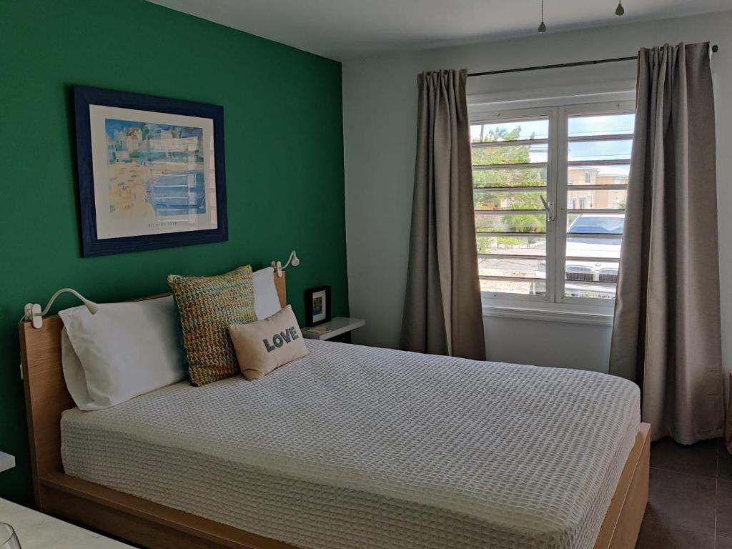 a bedroom with green walls and a bed with a window at Modern Studio in Pelican with pool-walk to Beach, Dining, Entertainment in Simpson Bay