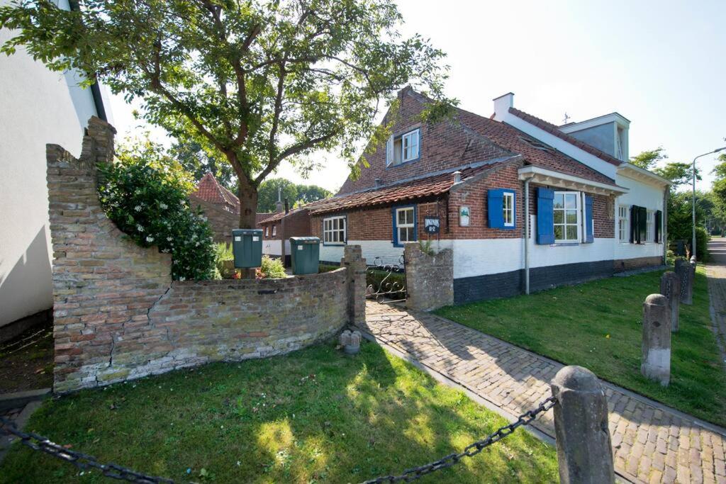 a brick house with a fence in front of it at Charming house in Westenschouwen in Burgh Haamstede