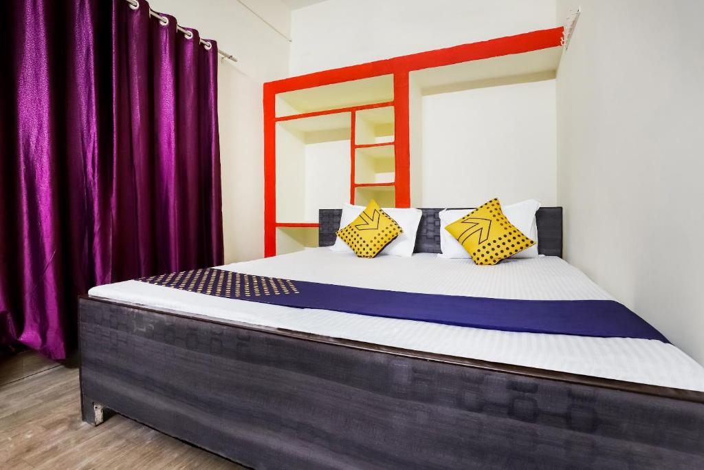 a bed in a room with purple curtains at Hotel O Tirupati Guest House in Gwalior