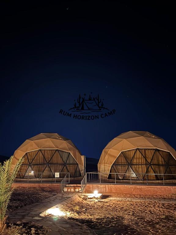 Dos cúpulas con el letrero del campamento de Houston por la noche. en Rum Horizon luxury camp, en Wadi Rum