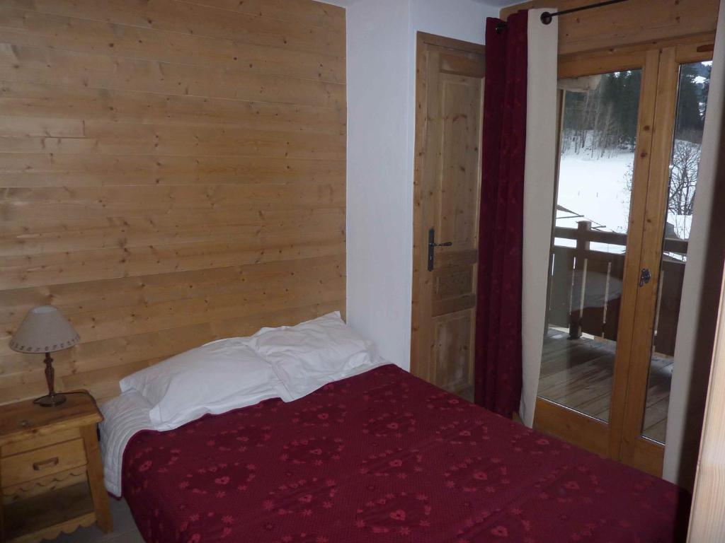 Un dormitorio con una cama con una pared de madera. en Le Hameau des Neiges, en Demi-Quartier