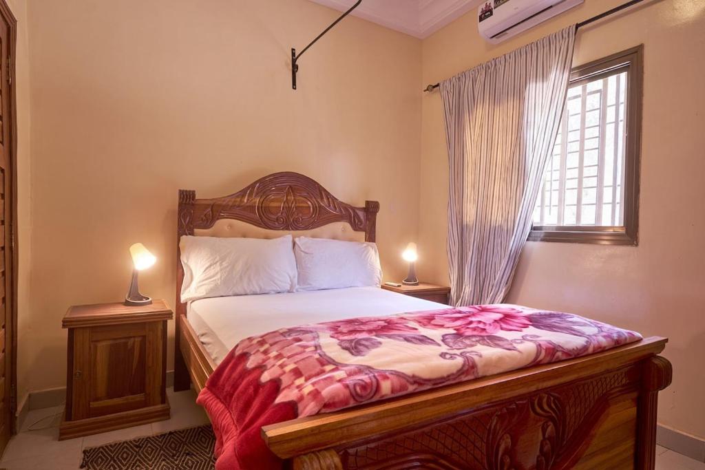 une chambre avec un lit avec deux tables de nuit et une fenêtre dans l'établissement Tekrour- la case des hotes - Chambre individuelle avec piscine et terrasse, à Mbour