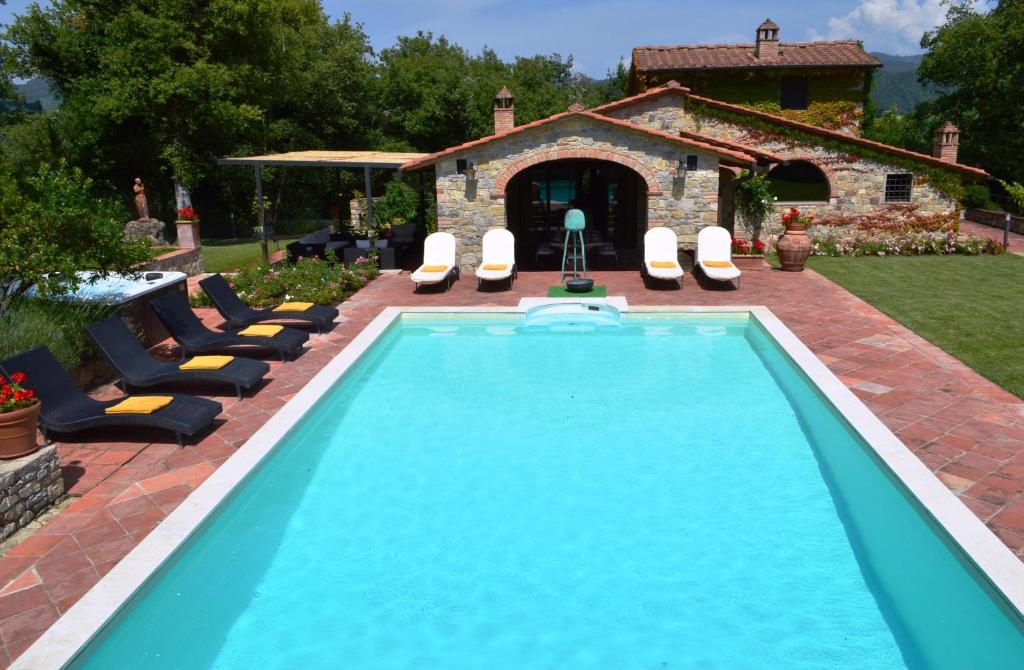 uma piscina com cadeiras e uma casa em Sestuccia em Gaiole in Chianti