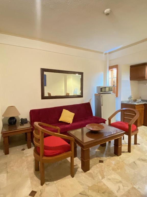 un salon avec un canapé rouge et une table dans l'établissement Thomas Coastal Apartment at Jayakarta Residence, à Seminyak