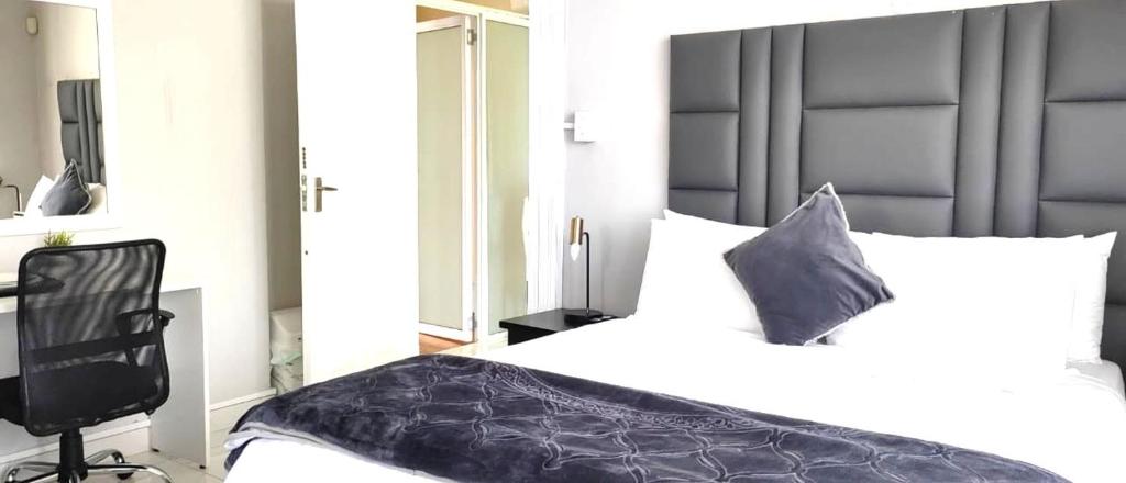 a bedroom with a bed and a desk and a chair at Stay-Tiah Whyte, Durban in Durban