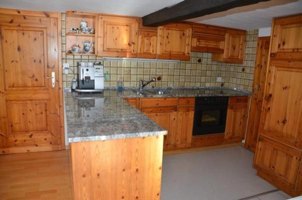 Una cocina con gabinetes de madera y encimera de granito. en Breiten, en Brunnadern
