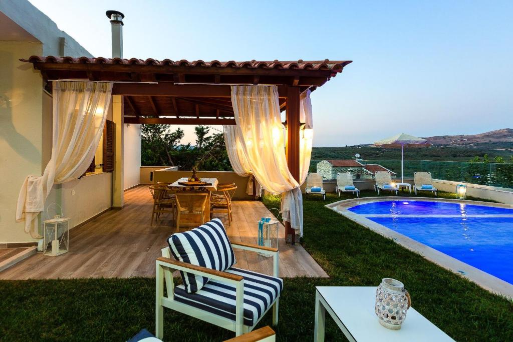 a patio with a table and chairs next to a swimming pool at Kampos Villa Iii in Achlades