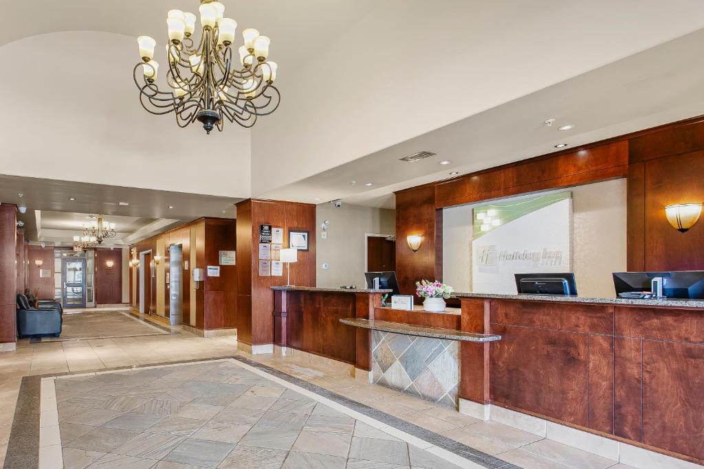 a hotel lobby with a reception desk and a chandelier at Holiday Inn & Suites Lloydminster by IHG in Lloydminster