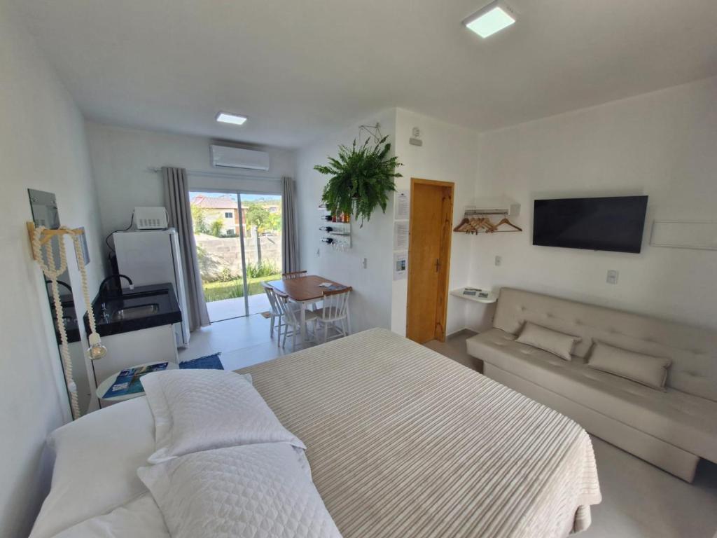 a bedroom with a bed and a couch and a television at Palo Santo - Praia do Rosa in Praia do Rosa