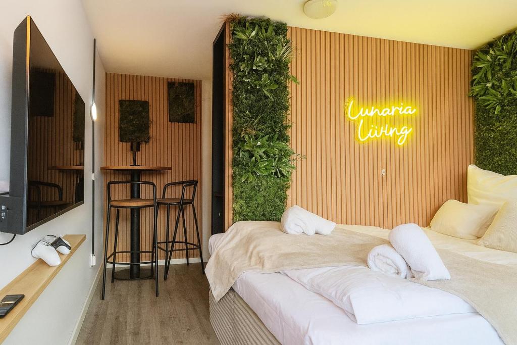 a room with two beds and a table with a television at Lunaria Living I Studio - Ambilight 55 Zoll TV - Retro-Konsole -Parkplatz - Zentral - HBF-nah & VW-Tor 17 in Wolfsburg