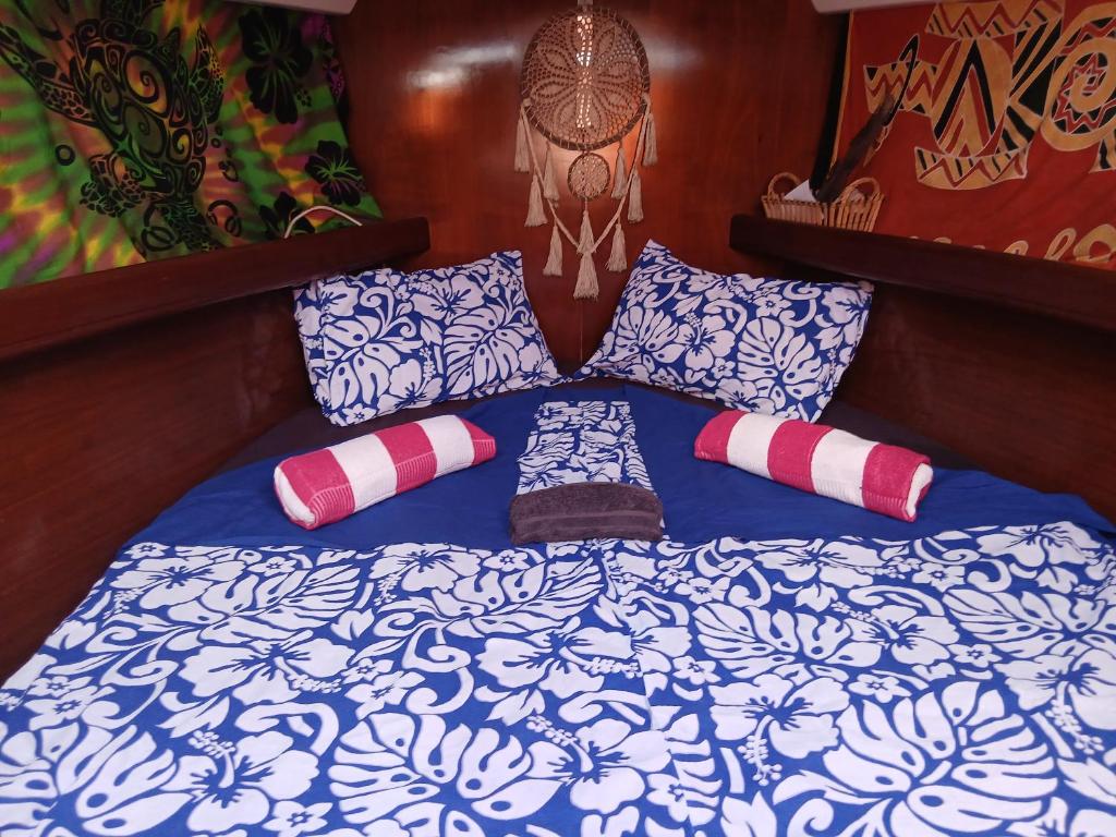 una cama con sábanas y almohadas azules y blancas en Bora Bora ou Maupiti sur un voilier, en Ataiti