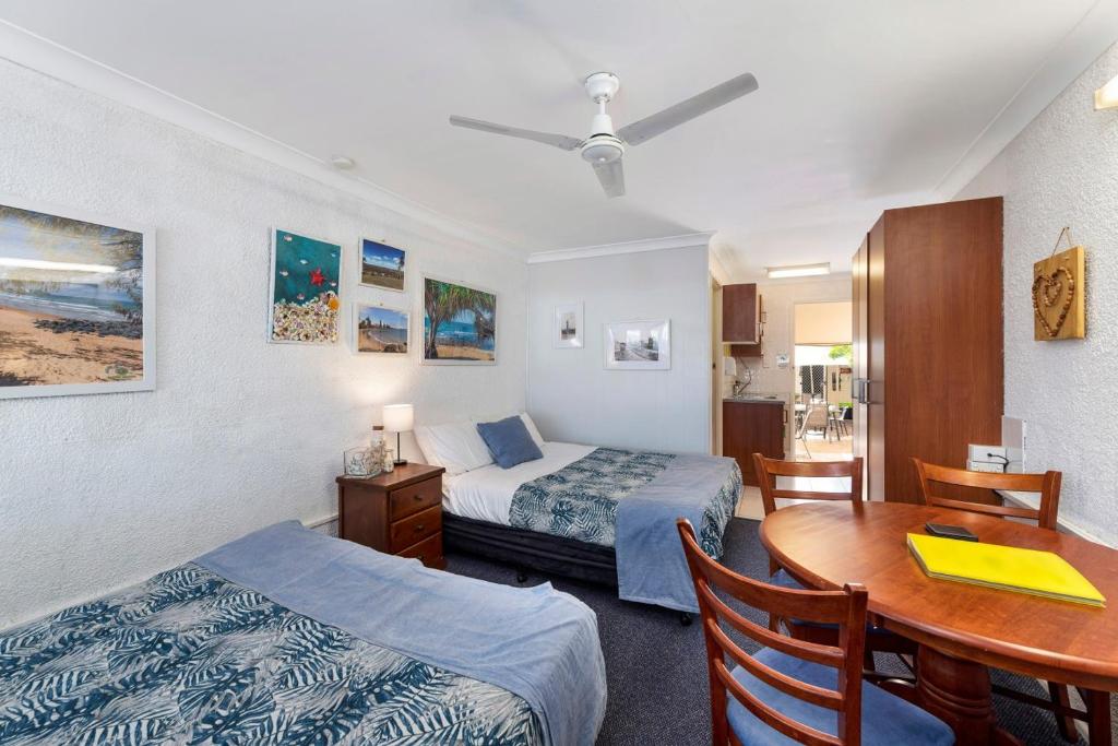 a hotel room with two beds and a table and a desk at Bundaberg Coral Villa Motor Inn in Bundaberg