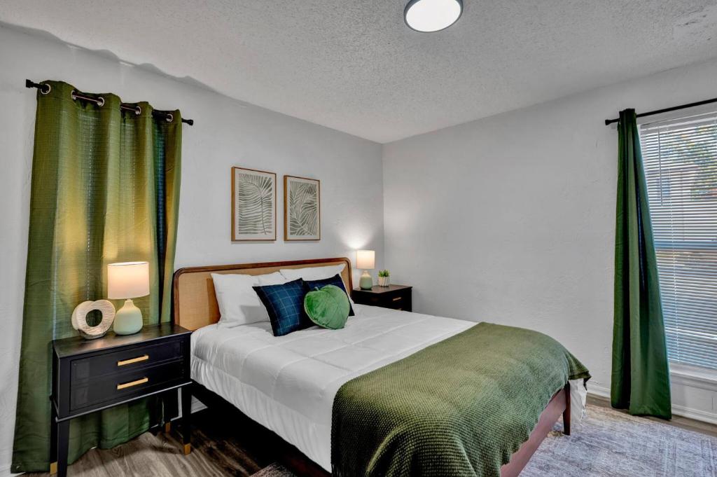 a bedroom with a large bed with green curtains at Near Boone Pickens Stadium - Stillwater Stay in Stillwater