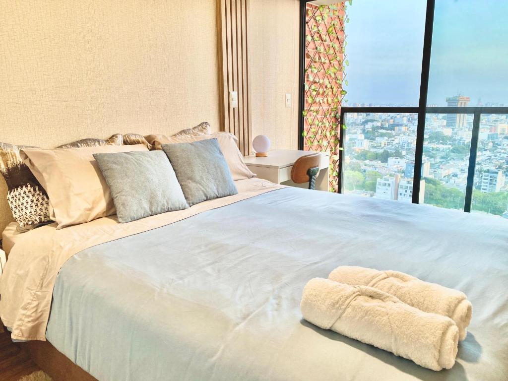 un grande letto bianco in una stanza con una grande finestra di Apartment with a view of San Isidro a Lima