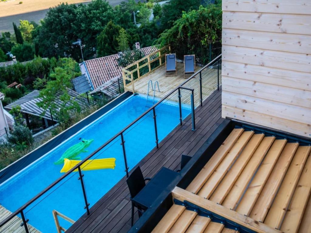 a swimming pool with a wooden deck and a swimming poolvisor at Mountain-view eco-friendly cottage in Marcoux