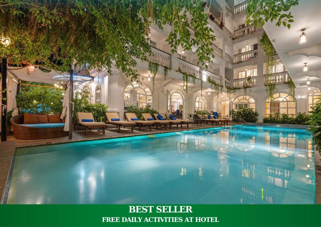 a large swimming pool in a building with tables and chairs at Hoi An Blue Sky Boutique Hotel & Spa in Hoi An
