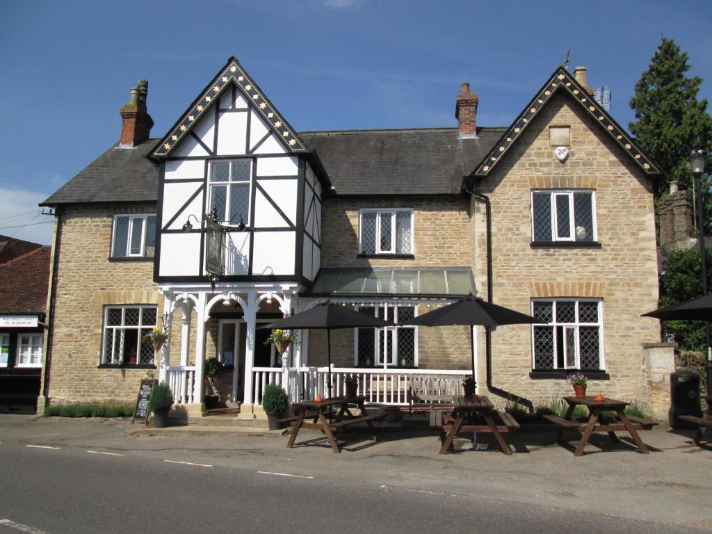 a building with tables and umbrellas in front of it at Three-Cranes in Turvey