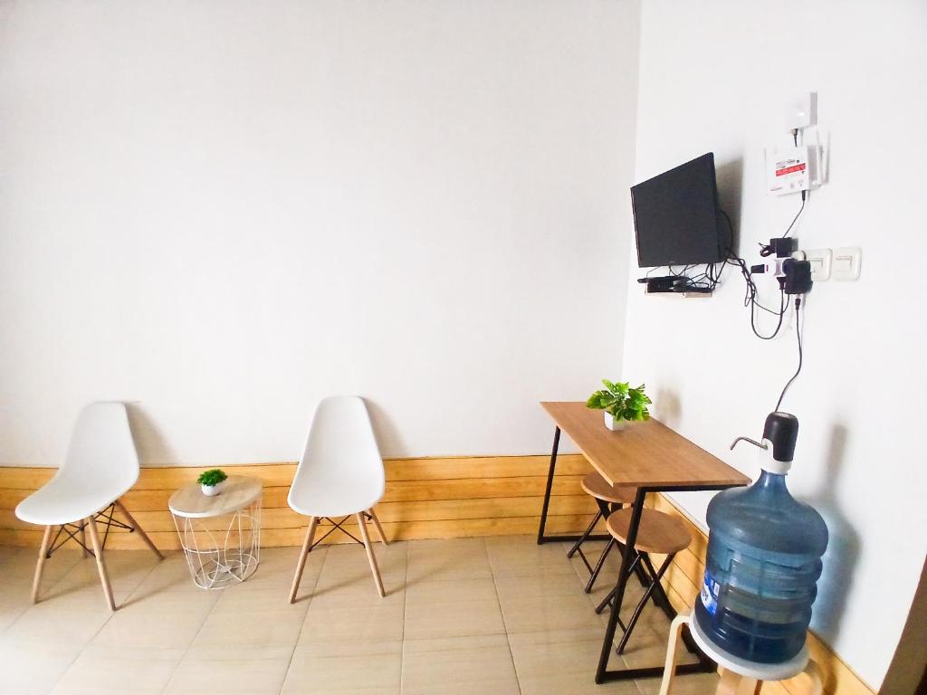 ein Zimmer mit drei Stühlen und einem Tisch mit einer Wasserflasche in der Unterkunft Homestay Nyaman di Pusat Kota in Blimbing