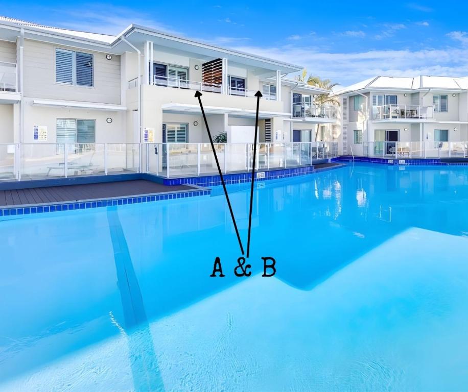 a b in front of a house and a swimming pool at Pacific Blue Poolside Escape - Oaks Port Stephens Pacific Blue Resort in Salamander Bay