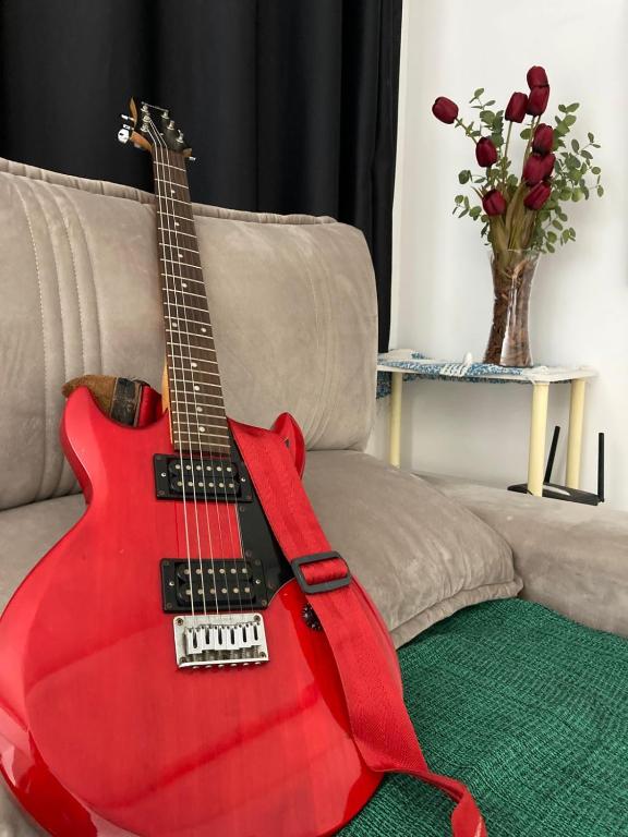 a red guitar sitting on top of a couch at NoiZ Apartment - SofaHouse in Rio das Ostras