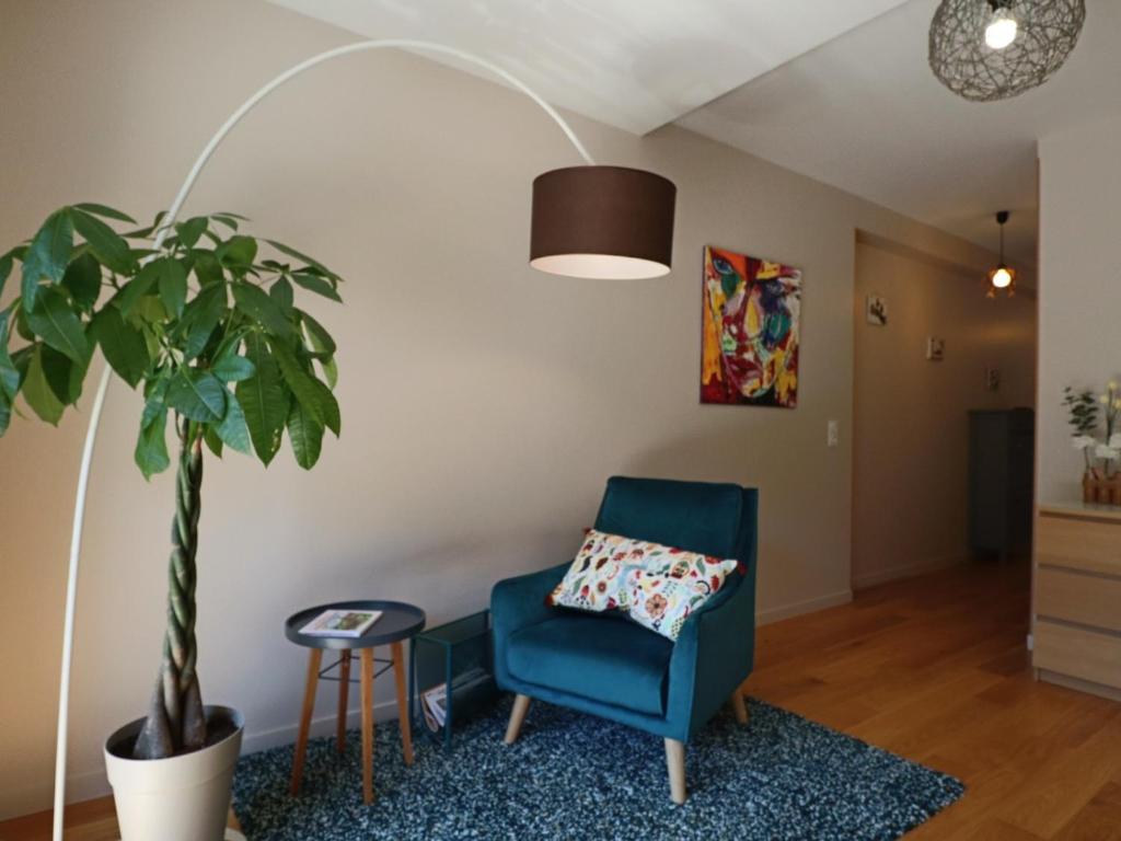un salon avec une chaise bleue et une plante en pot dans l'établissement Appartement chaleureux 6 pers avec terrasse au Mont-Dore - FR-1-858-31, à Mont-Dore