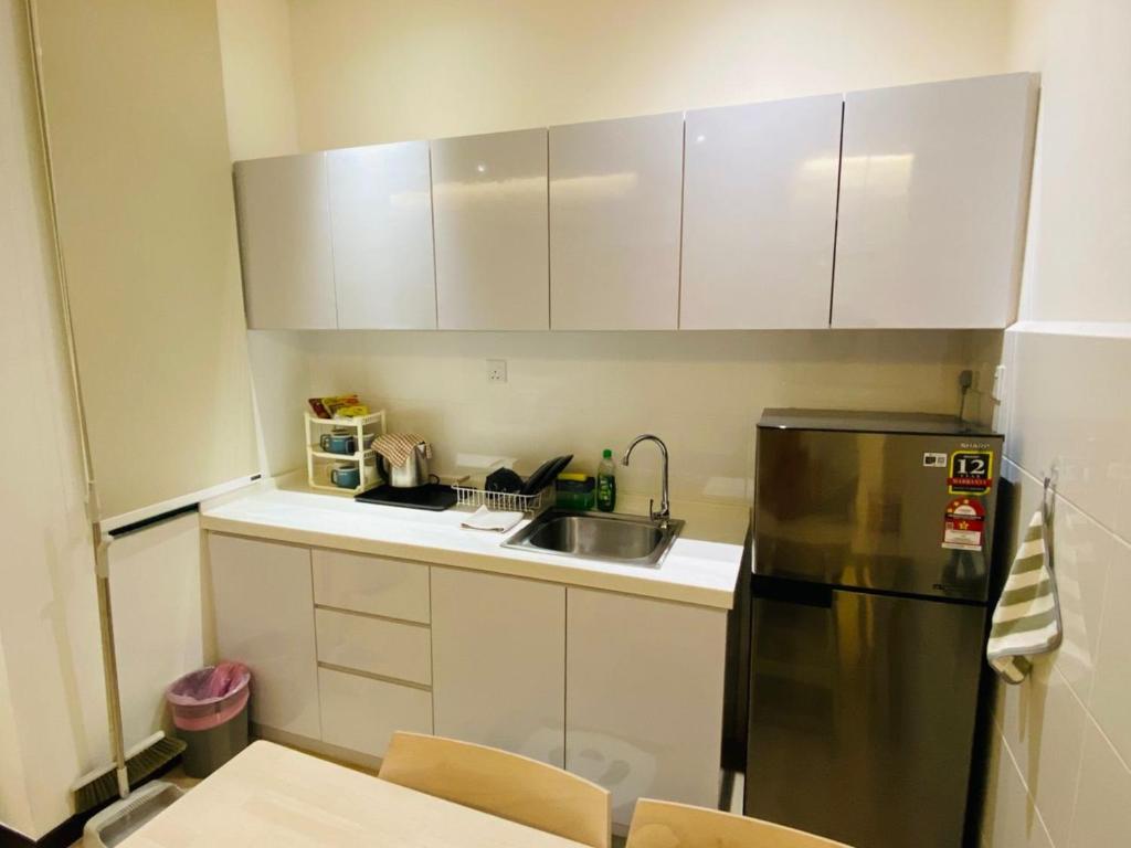 eine Küche mit einem Edelstahlkühlschrank und weißen Schränken in der Unterkunft Majestic Manhattan Suites ITCC in Penampang