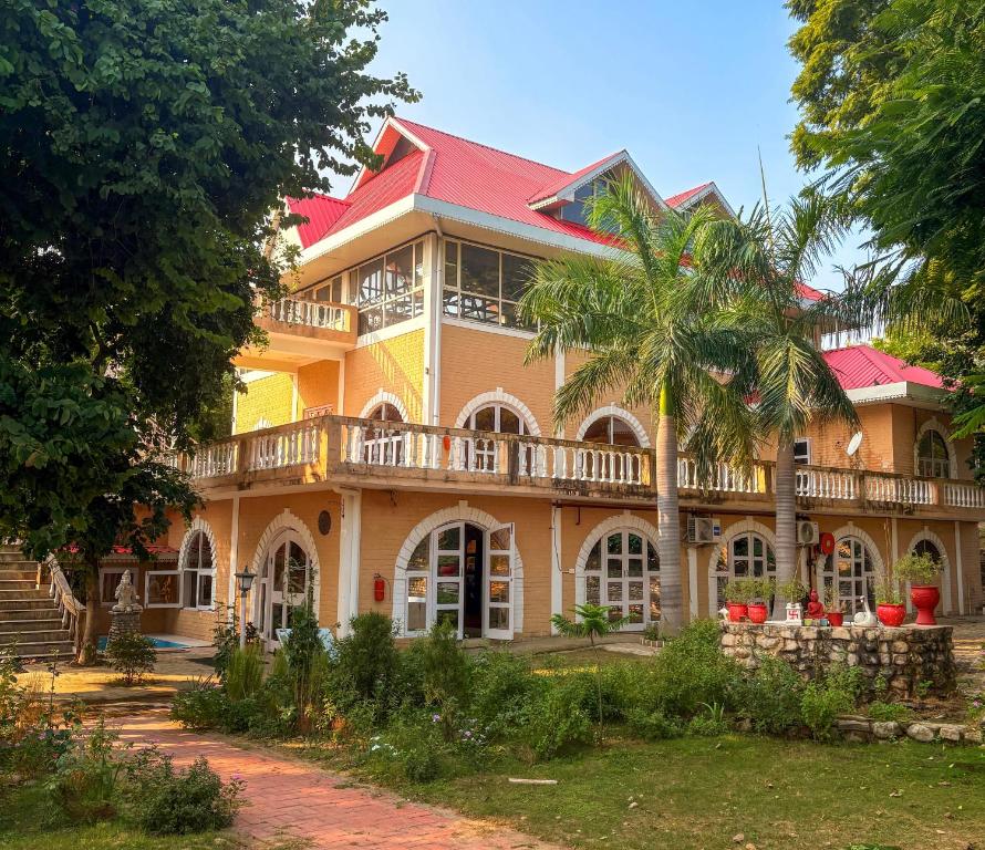 a large house with a palm tree in front of it at Prakriti Farms in Rūpnagar
