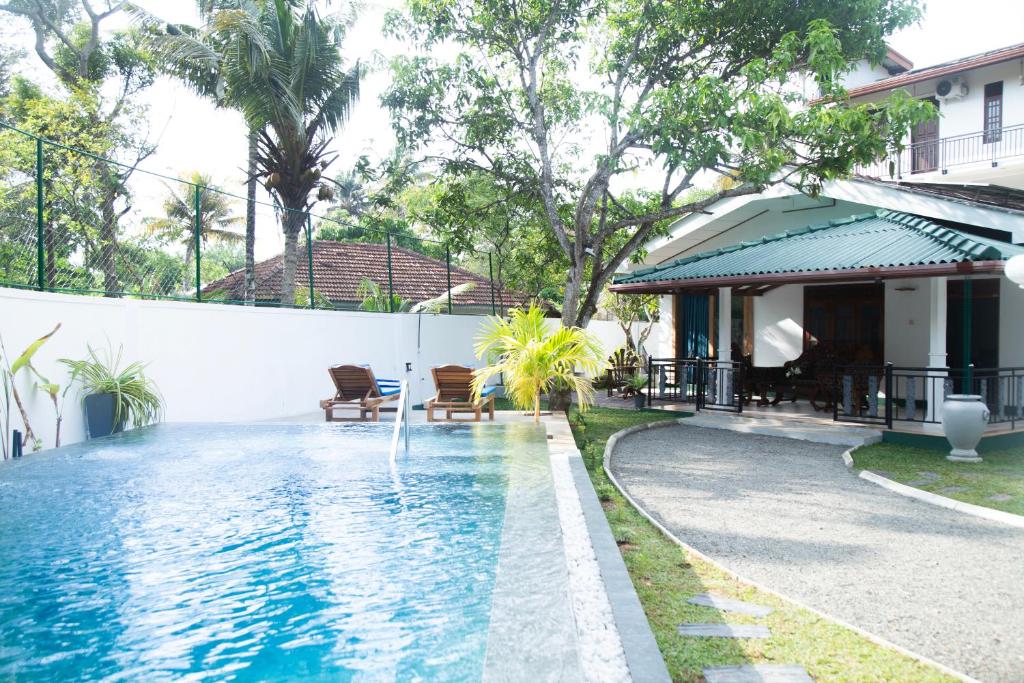a swimming pool with a fountain in front of a house at Sea Bloom Villa in Kamburugamuwa