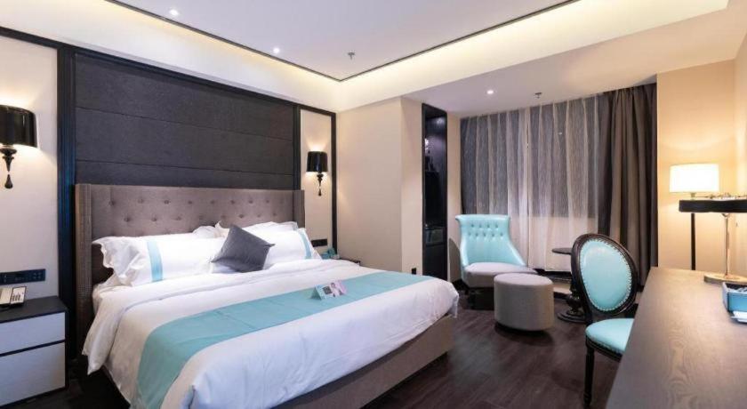 a hotel room with a large bed and a chair at Xana Hotelle· Wulumuqi High Speed Railway Station Baonengcheng in Ürümqi